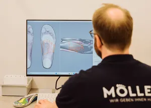 Mitarbeiter von hinten vor einem Bildschirm, auf dem die Diabetesbettung für Schutzschuhe erstellt wird